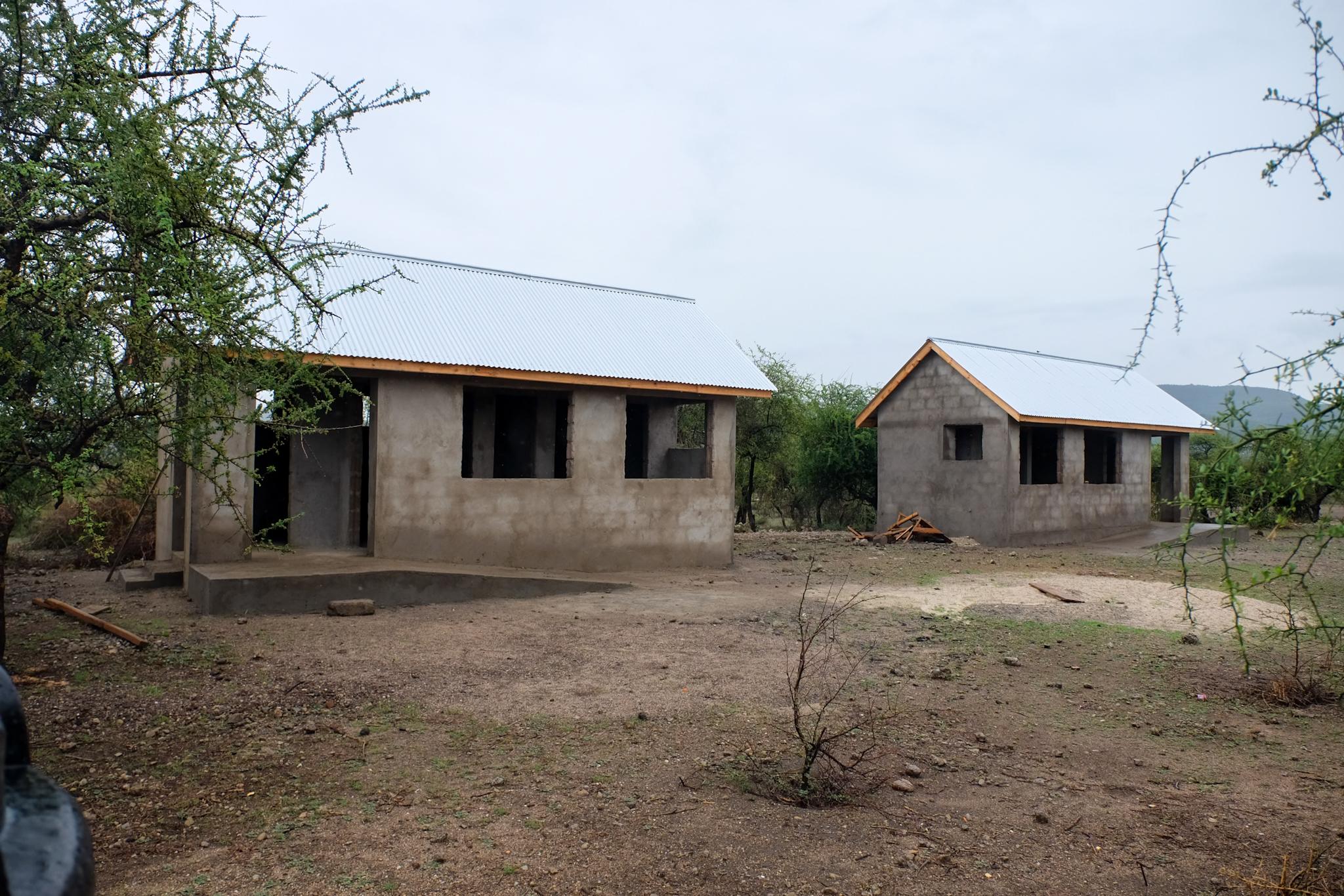 Kinder und Schulgebäude der Esilalei Primary School in Mto Wa Mbu, Tansania, wo AKO neue Toiletten und Klassenräume unterstützt.